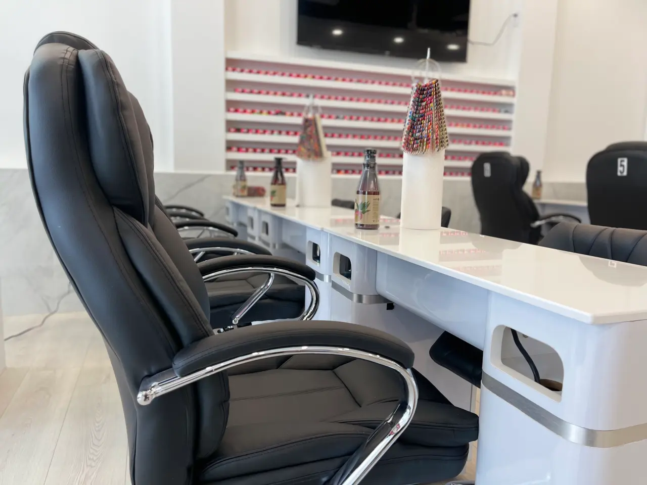 High-back plush manicure chair at the white manicure bar with gel colour wall behind at Aivia Nails in Cranbrook