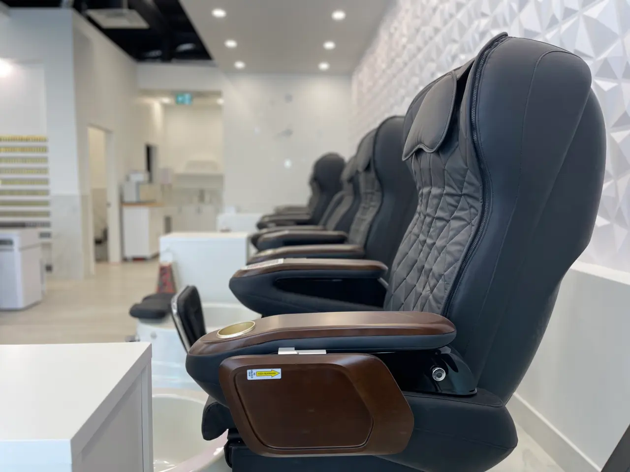 Quilted black pedicure massage throne with walnut armrests and cup holder at Aivia Nails in Cranbrook